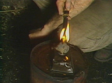 Charles heats his knife and prepares to tend to his wound